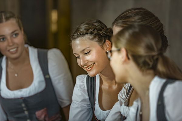 Vier Mitarbeiterinnen des Platzl-Hotels stehen gemeinsam an der Rezeption und besprechen sich