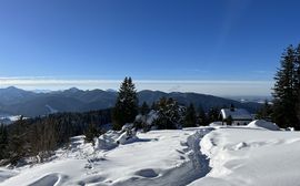 Winterliche Berglandschaft mit Hütte und Panoramablick auf die Alpen