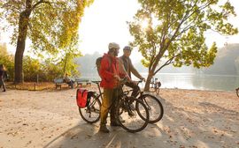 Zwei sportliche Fahrradfahrer im Englischen Garten München vor einem kleinen See.