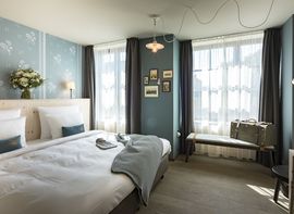 Großzügiges Doppelbett mit Wärmflasche und Kuscheldecke im Doppelzimmer Gundi des Boutique Hotel München