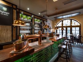 Die Bar im Ayinger am Platzl glänzt mit Kupfertheke, Zapfanlage und stimmungsvollem Licht
