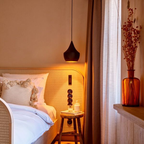 Shot of a new suite at Platzl Hotel with modern lamp, wooden nightstand, comfortable bed and flower vase.