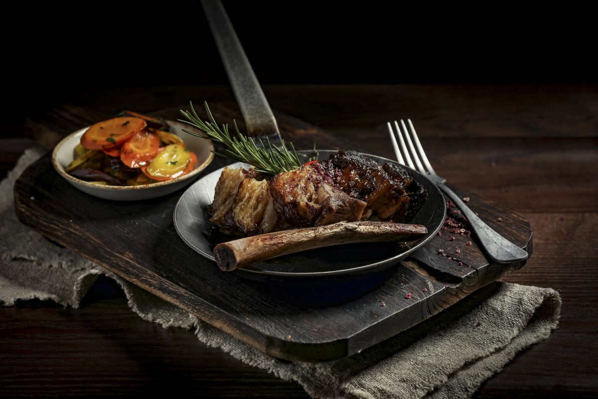 A hearty meat dish with side salad served on plates and placed over a rustic wooden board.