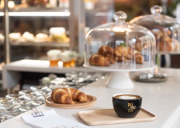 Einige Croissants und ein Cappuccino in einer Tasse der Josefa steht auf einer Theke.