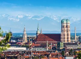 [Translate to Englisch:] Blick über die Münchner Altstadt mit den Türmen der Frauenkirche vor den Alpen im Hintergrund.