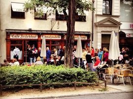 Exterior shot of Café Frischhuts with waiting visitors in front of the entrance.