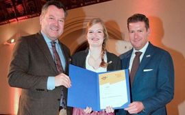 Three people celebrate the Platzl Hotel's "Münchner Ökoprofit-Betrieb" award.