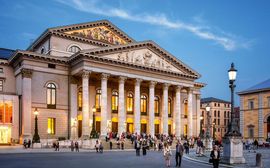 Evening view of the Bavarian State Opera with glowing lights and people outside